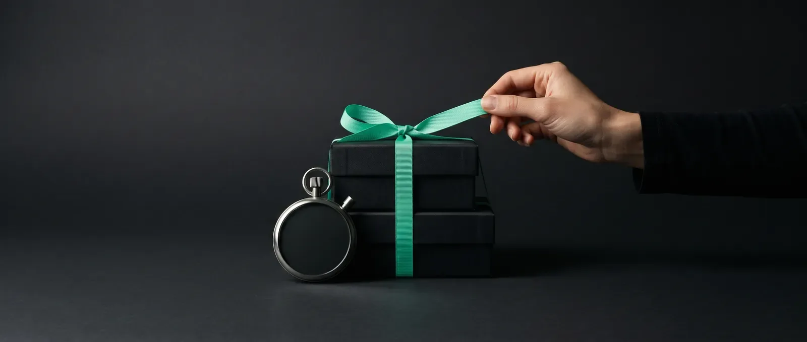 Dłoń rozwiązuje miętową wstążkę na stosie pudełek - start kampanii klienta e-commerce w Black Week